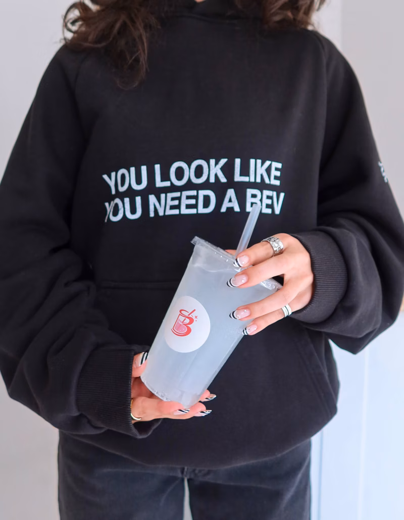 Guests holding up colorful The Bev signature drinks